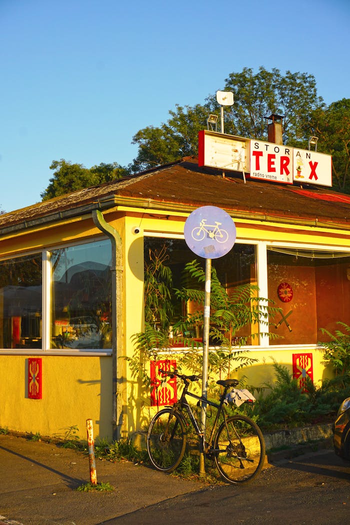 A bicycle parked beside a sign outside a colorful diner in Belgrade, Serbia.